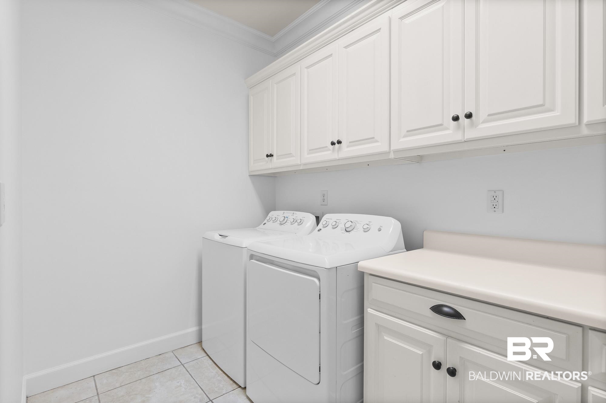 11261 Halcyon Loop Daphne, AL 36526 - Photo 29 of 41 Laundry area featuring white cabinetry with black hardware, a light-toned countertop, and tiled flooring