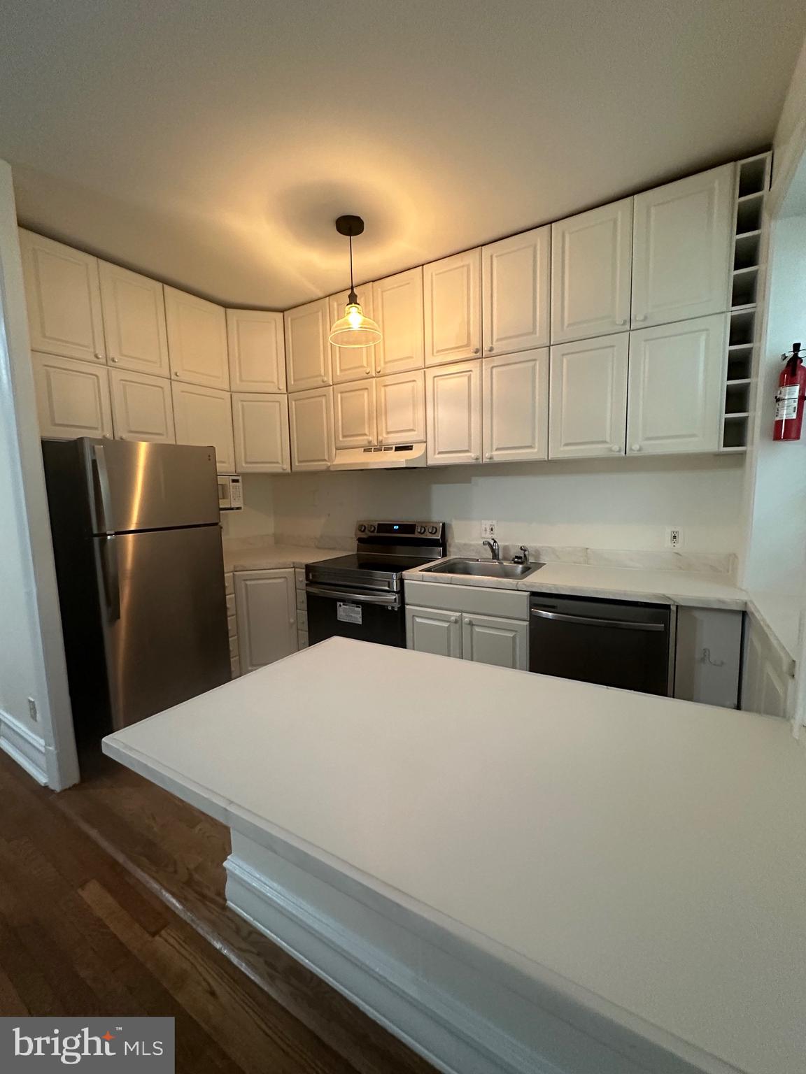 3420 16th Street Northwest, Unit 103 Washington, DC 20010 - Photo 14 of 24 a kitchen with stainless steel appliances a refrigerator a sink a stove and white cabinets