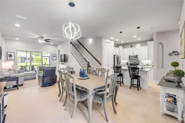 a kitchen with stainless steel appliances a dining table chairs refrigerator and microwave