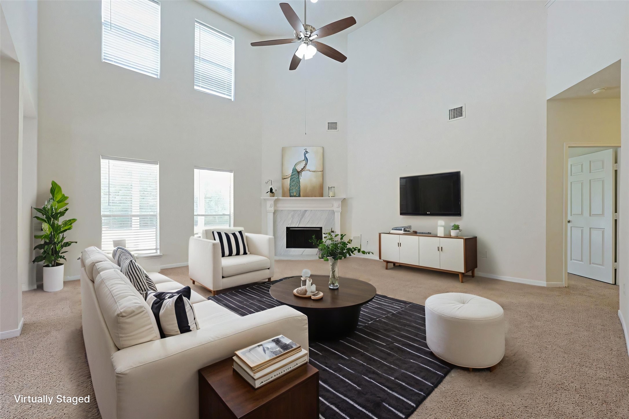 23019 Eastgate Village Drive Spring, TX 77373 - Photo 1 of 46 Virtually staged living room with high ceilings and abundant natural light. It features a cozy fireplace, modern furnishings, and a ceiling fan, creating an inviting and comfortable atmosphere.