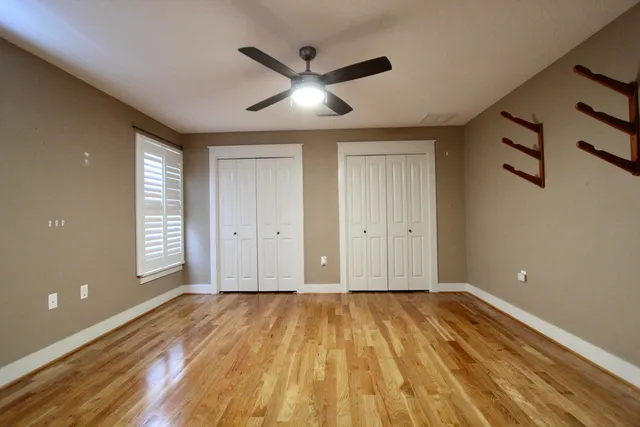 a view of empty room with wooden floor and fan