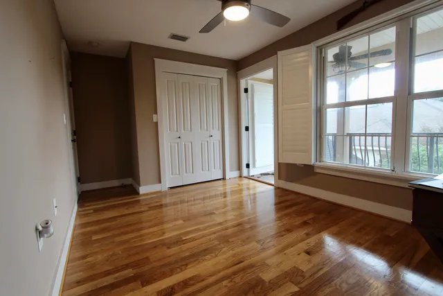 a view of an empty room with window and wooden floor
