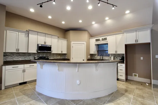 a large kitchen with stainless steel appliances granite countertop a stove a sink a refrigerator and a microwave