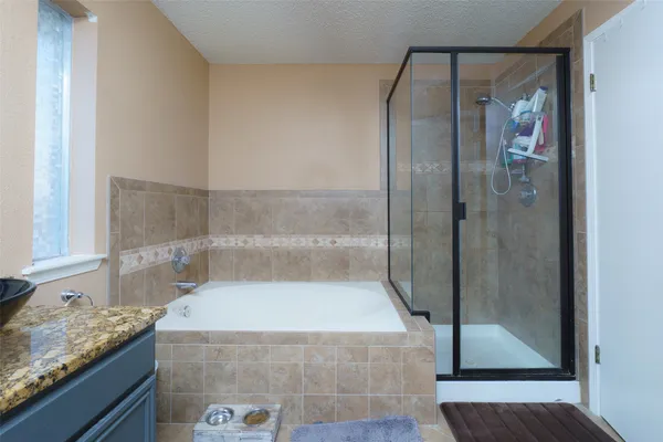 a bathroom with a granite countertop bathtub shower and sink