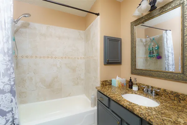 a bathroom with a granite countertop bathtub shower sink and mirror