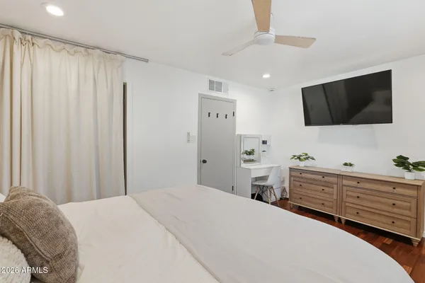 a bedroom with a large bed and a flat tv screen on dresser
