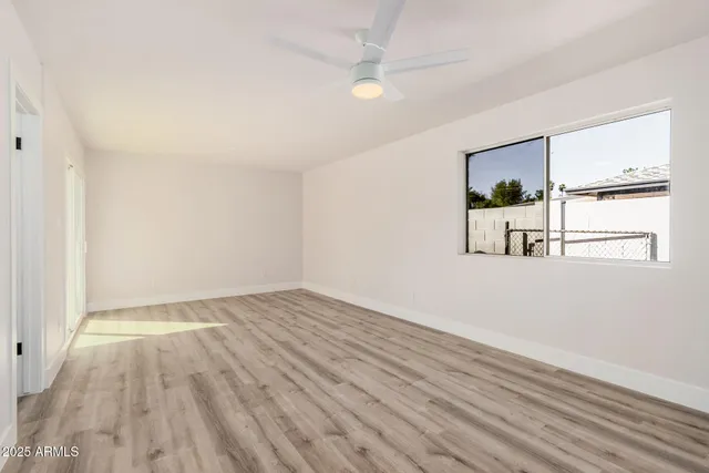 a view of empty room with wooden floor and fan