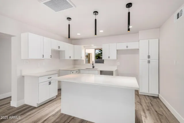 a kitchen with stainless steel appliances sink stove and white cabinets with wooden floor