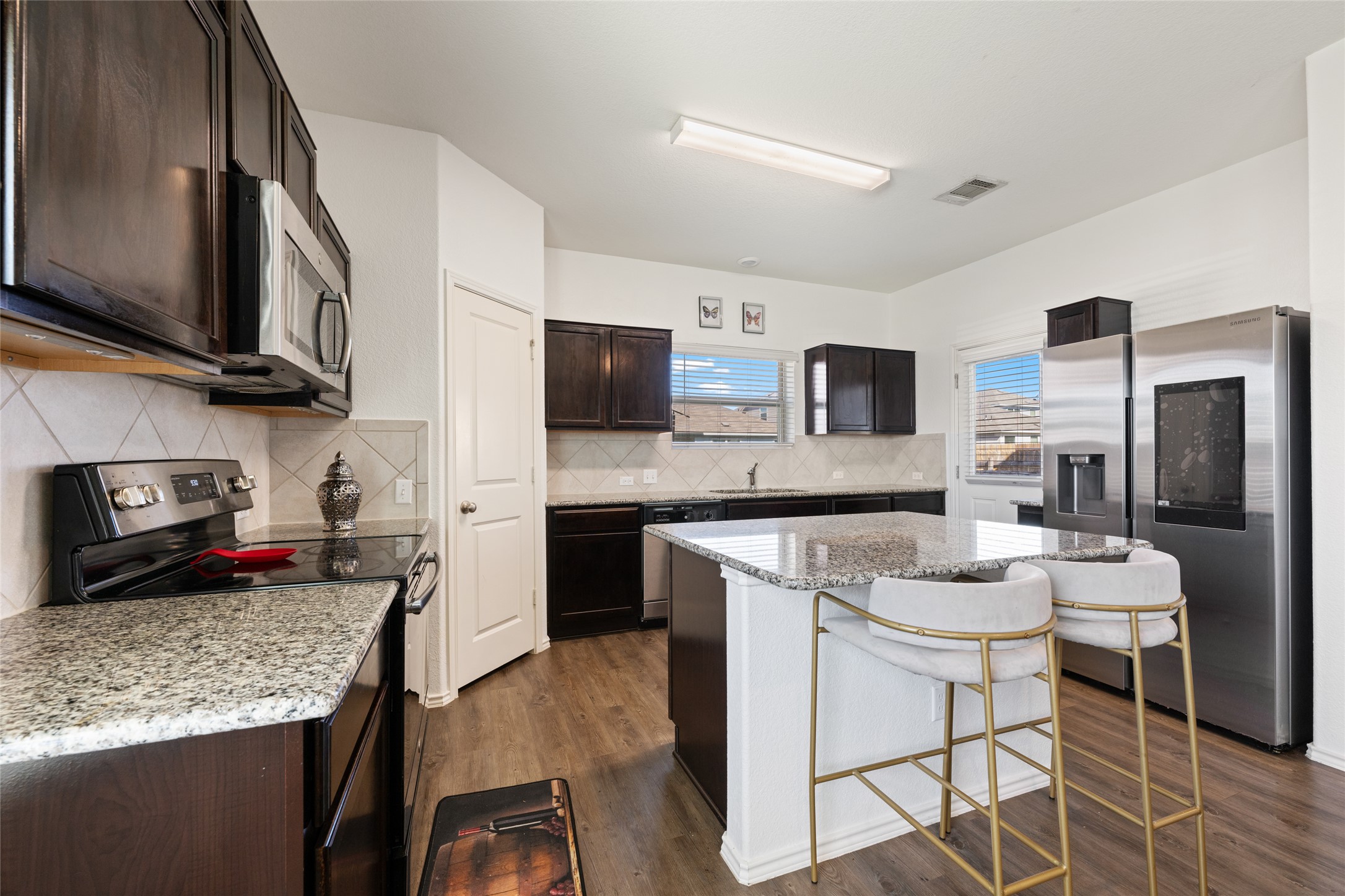 524 Circle Way, Unit 12F Jarrell, TX 76537 - Photo 11 of 34 Kitchen with stainless steel appliances, a breakfast bar, dark wood finish cabinets, dark wood-style flooring, and a kitchen island