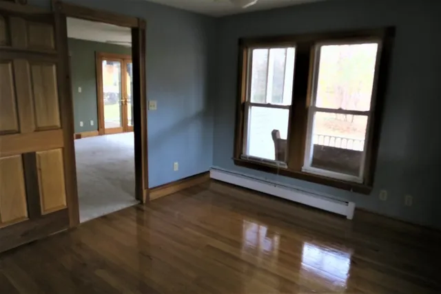 a view of an empty room with wooden floor and a window