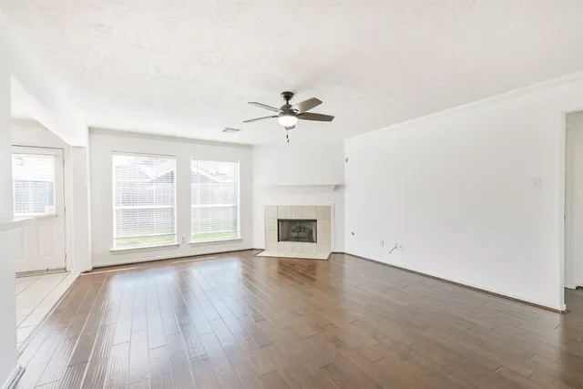 an empty room with wooden floor fan and windows