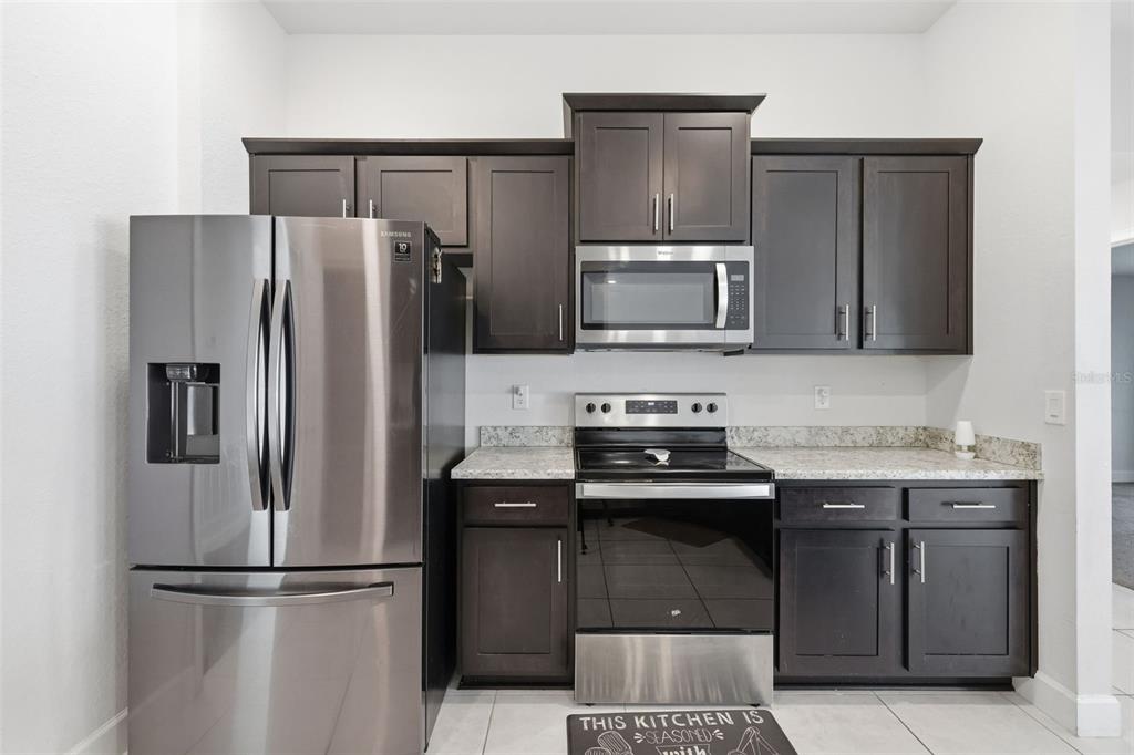 9144 Southeast 47th Court Road Ocala, FL 34480 - Photo 12 of 32 a kitchen with granite countertop a refrigerator and a stove top oven
