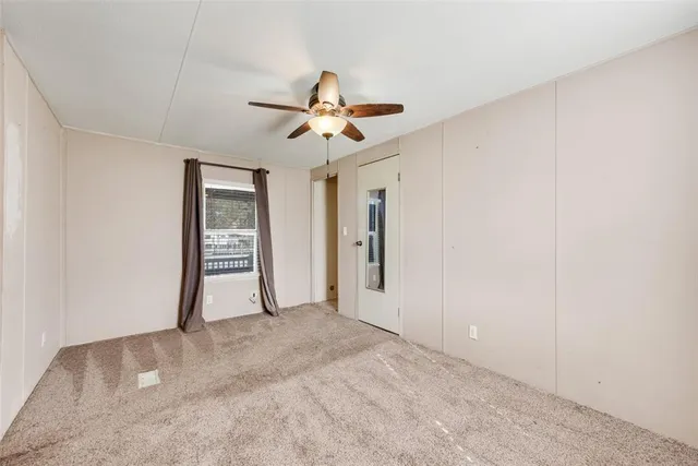 an empty room with closet and a ceiling fan
