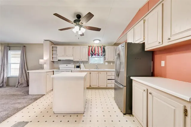 a kitchen with a refrigerator a sink and dishwasher with white cabinets