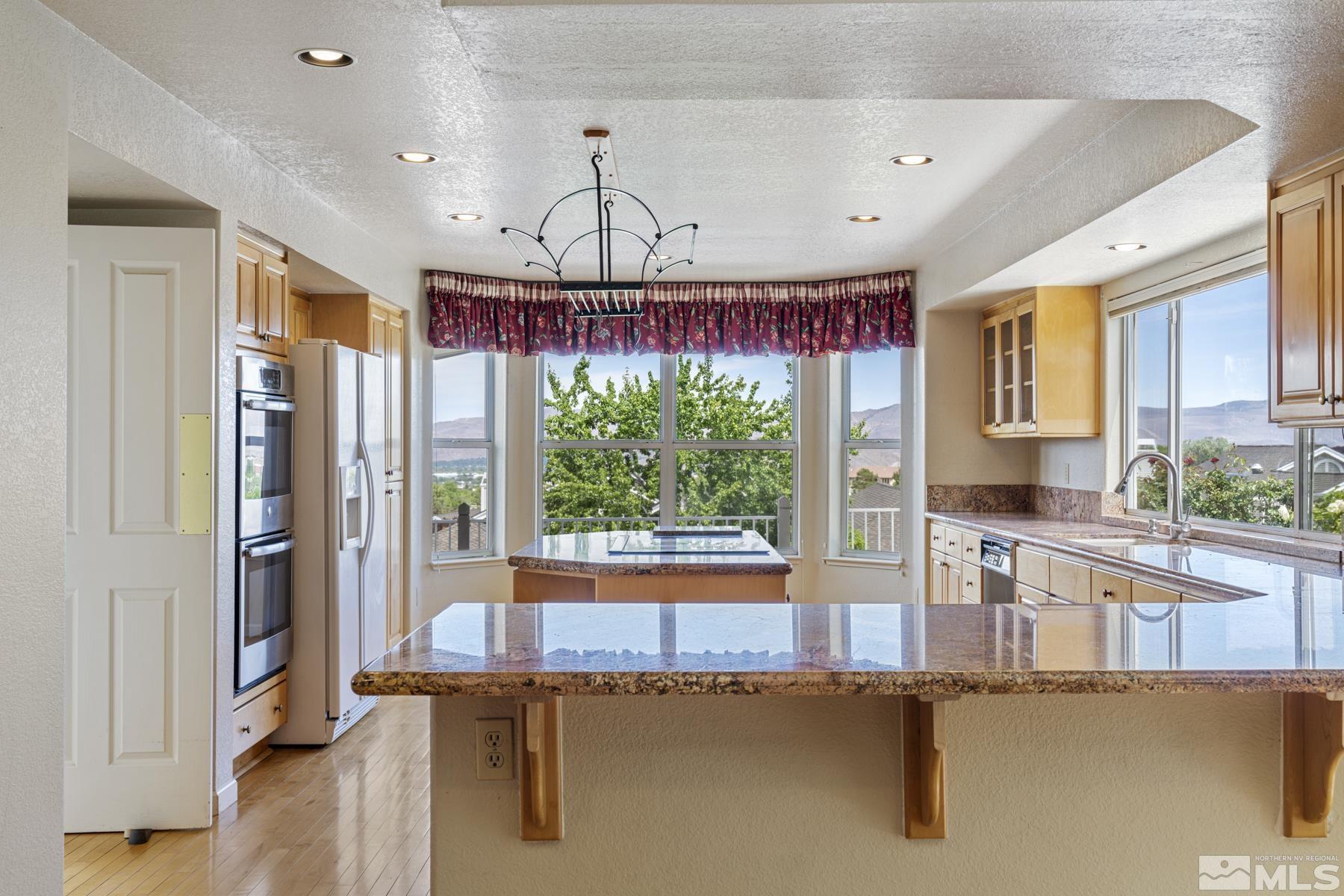 6172 Squires Lane Reno, NV 89519 - Photo 11 of 40 a kitchen with stainless steel appliances granite countertop a refrigerator a stove and a sink with wooden floor