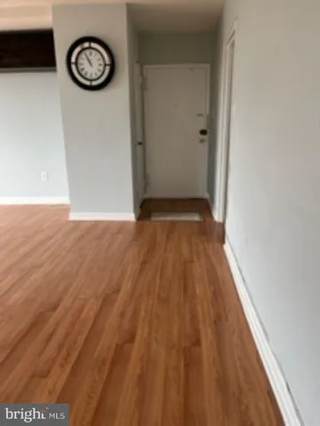 a view of a room with wooden floor and a clock on wall