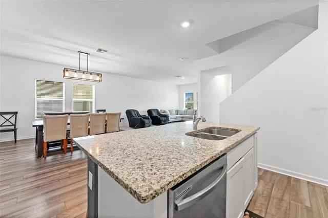 a kitchen with a kitchen island a sink dishwasher a dining table and chairs with wooden floor