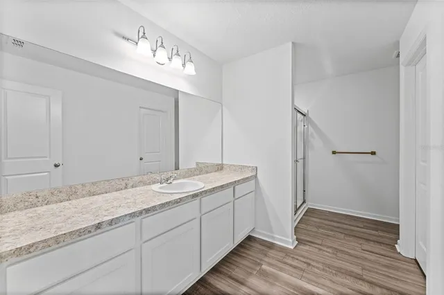 a bathroom with a granite countertop double vanity sink and mirror