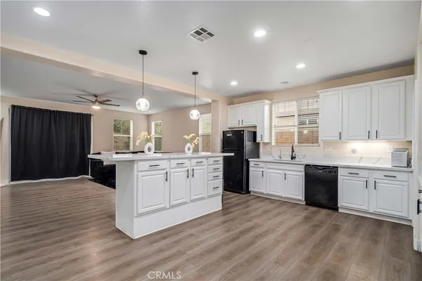 a large kitchen with granite countertop a large counter top space a sink stainless steel appliances and cabinets