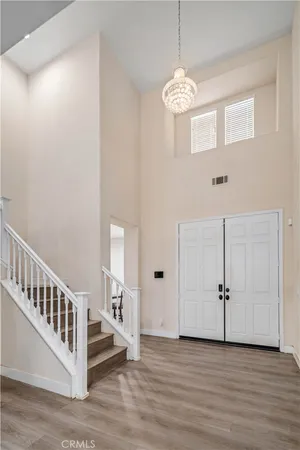 an empty room with wooden floor windows and a chandelier