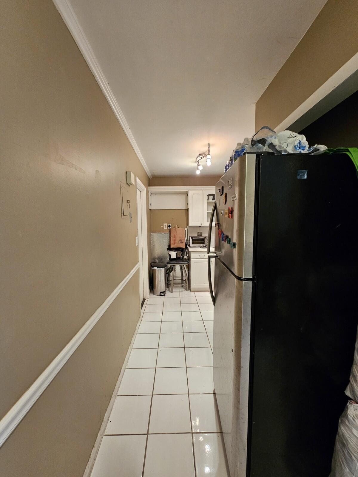 119 Northeast 19th Court, Unit 211G Wilton Manors, FL 33305 - Photo 14 of 21 a view of a hallway with a dining table chair and a refrigerator