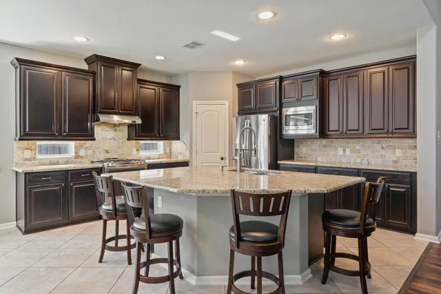 a kitchen with kitchen island granite countertop wooden cabinets and stainless steel appliances