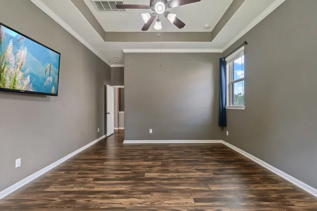 a view of an empty room with window and wooden floor