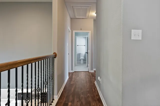 a view of a hallway with wooden floor and a bathroom