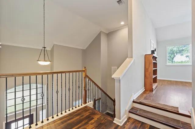 a view of staircase with lots of frames on wall and wooden floor