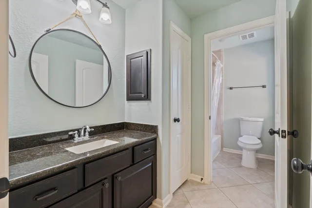 a bathroom with a granite countertop toilet sink and mirror