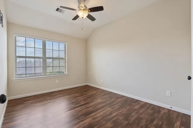 a view of empty room with wooden floor and fan