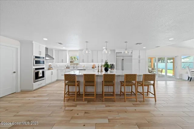a kitchen with stainless steel appliances kitchen island a table chairs sink and cabinets