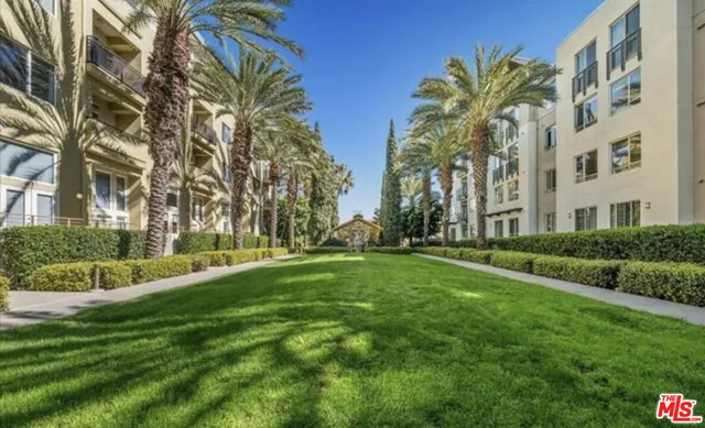 a view of a apartment with a big yard and large trees