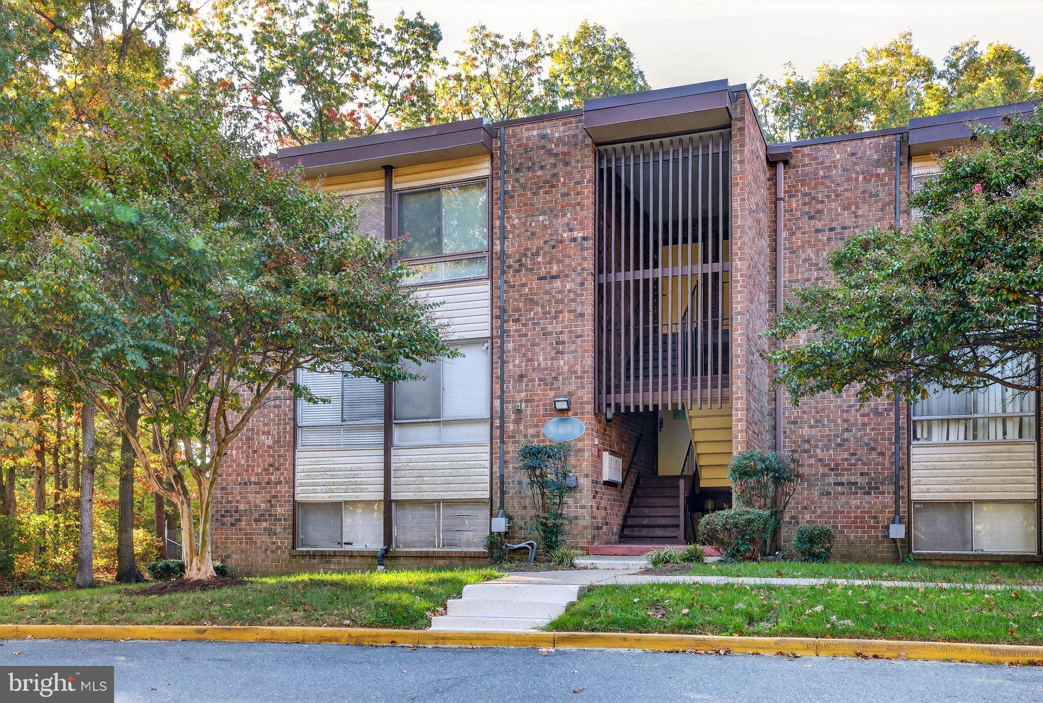 8481 Greenbelt Road, Unit 201 Greenbelt, MD 20770 - Photo 25 of 26 a view of a brick house with a yard plants and large tree