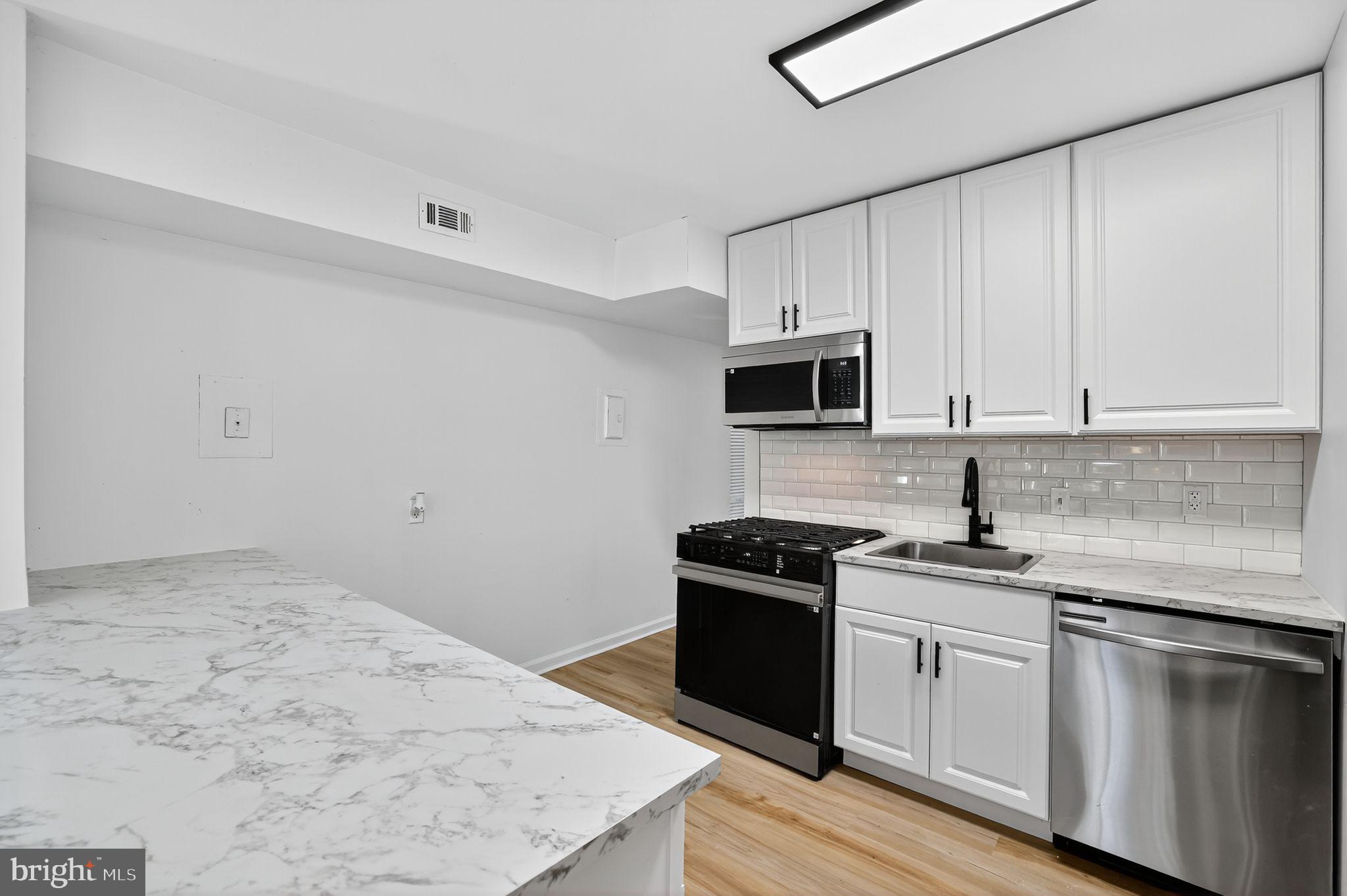 8481 Greenbelt Road, Unit 201 Greenbelt, MD 20770 - Photo 8 of 26 a kitchen with granite countertop white cabinets sink and stainless steel appliances