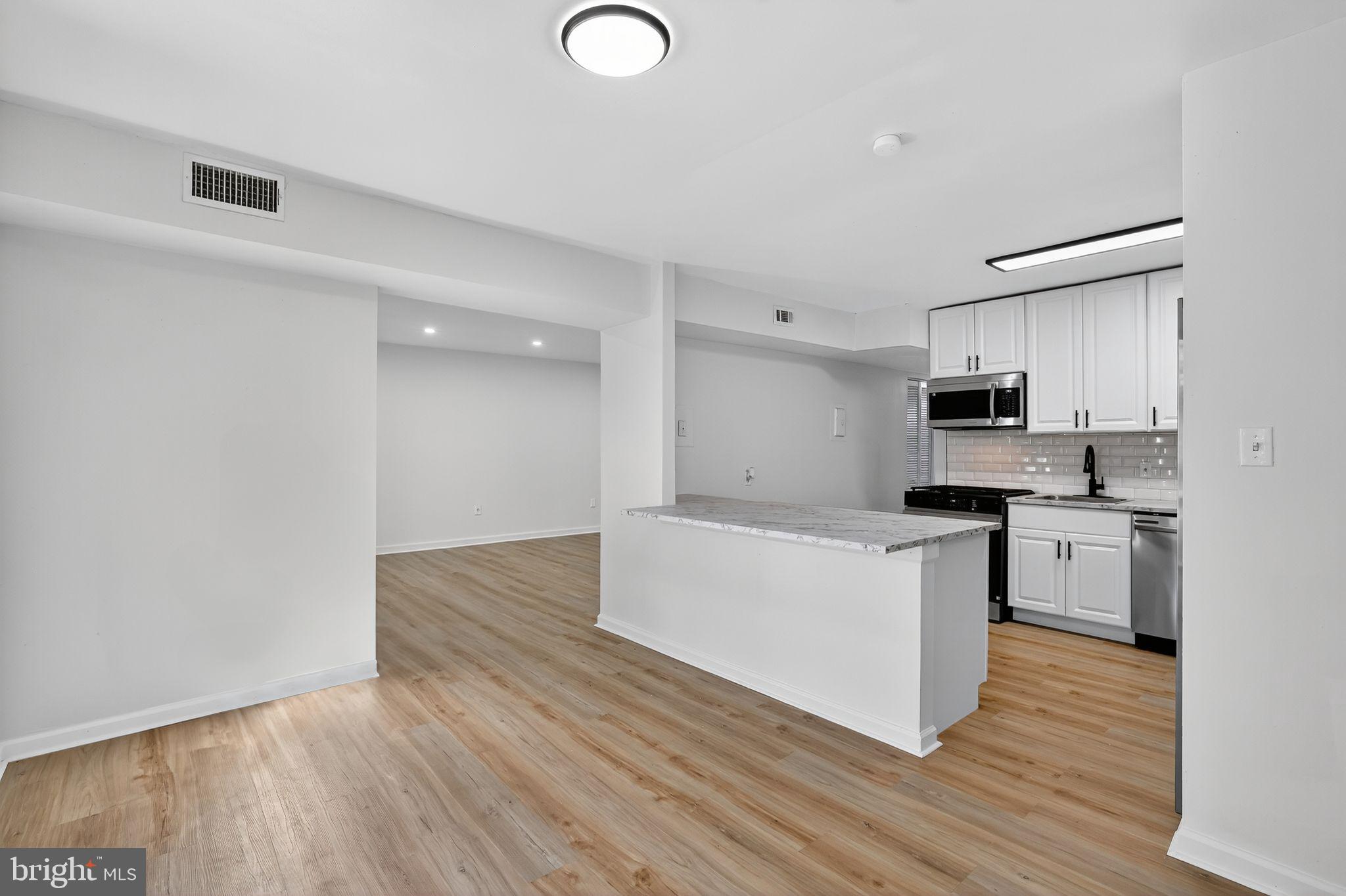 8481 Greenbelt Road, Unit 201 Greenbelt, MD 20770 - Photo 9 of 26 a kitchen with granite countertop a stove top oven and white cabinets