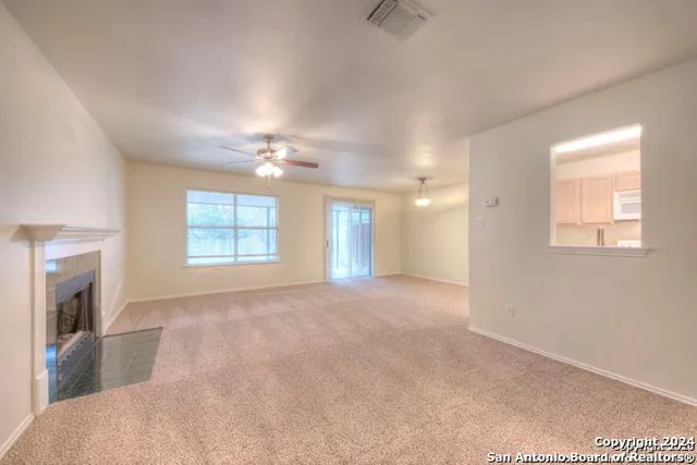 a view of an empty room with a fireplace and a window