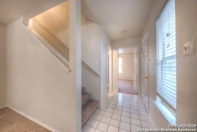 an empty room with a chandelier fan and windows