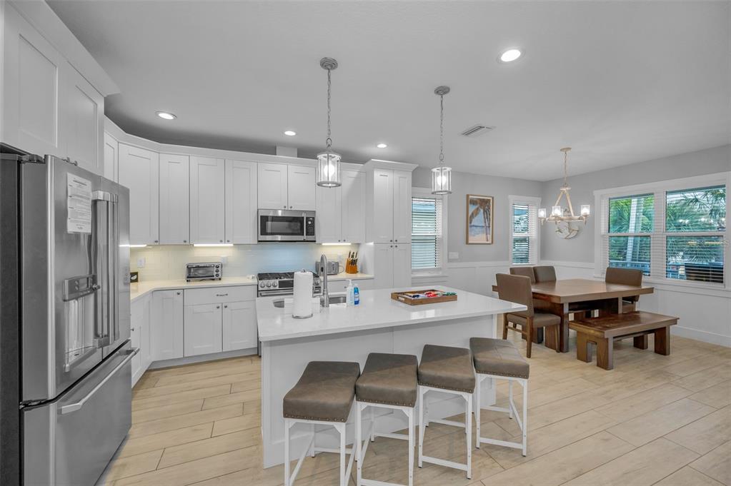 204 Gulf Boulevard Indian Rocks Beach, FL 33785 - Photo 33 of 72 a kitchen with stainless steel appliances kitchen island granite countertop a dining table chairs stove a refrigerator and cabinets