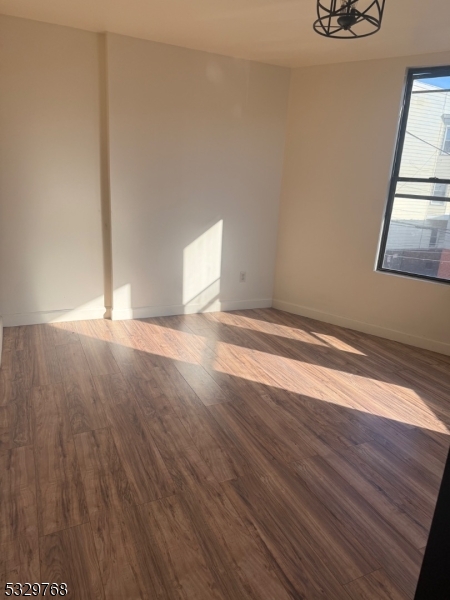 182 Ferry Street, Unit 2B Newark, NJ 07105 - Photo 5 of 16 a view of an empty room with wooden floor and a window