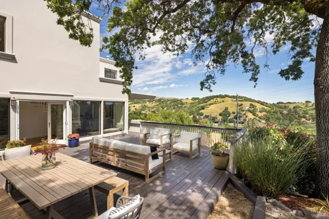 a view of a patio with couches table and chairs with potted plants and large tree