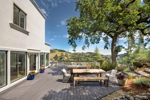 a view of a patio with table and chairs and floor to ceiling window plants and trees