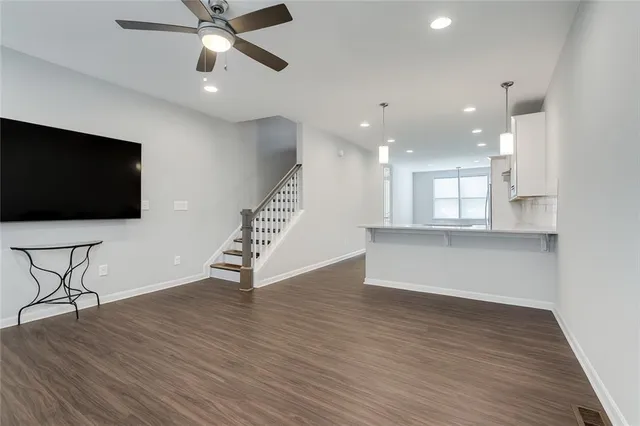 a view of an empty room with wooden floor and a ceiling fan