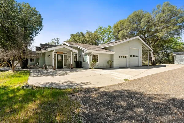 a front view of a house with a garden and trees