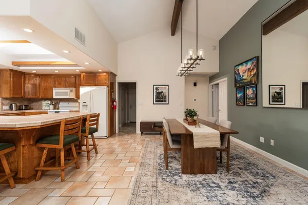 a kitchen with stainless steel appliances kitchen island granite countertop a table chairs and a refrigerator