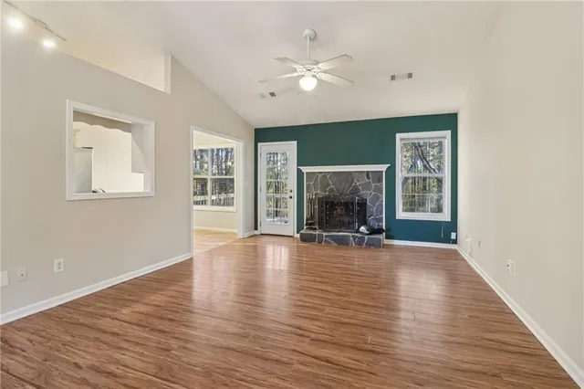 an empty room with wooden floor fireplace and windows
