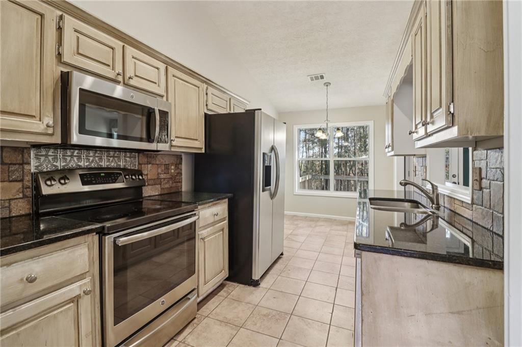 572 Casey's Crossing Winder, GA 30680 - Photo 7 of 31 a kitchen with granite countertop a stove and a microwave