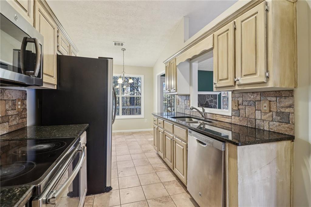 572 Casey's Crossing Winder, GA 30680 - Photo 8 of 31 a kitchen with stainless steel appliances granite countertop a stove top oven a sink dishwasher and a refrigerator
