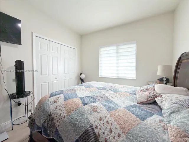 a bedroom with a bed tv and a window