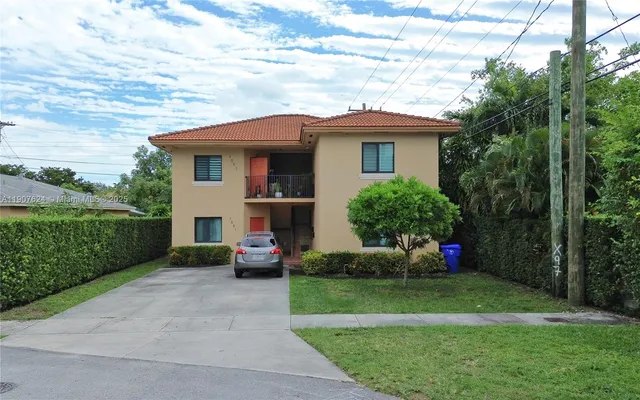 a front view of a house with a garden and trees